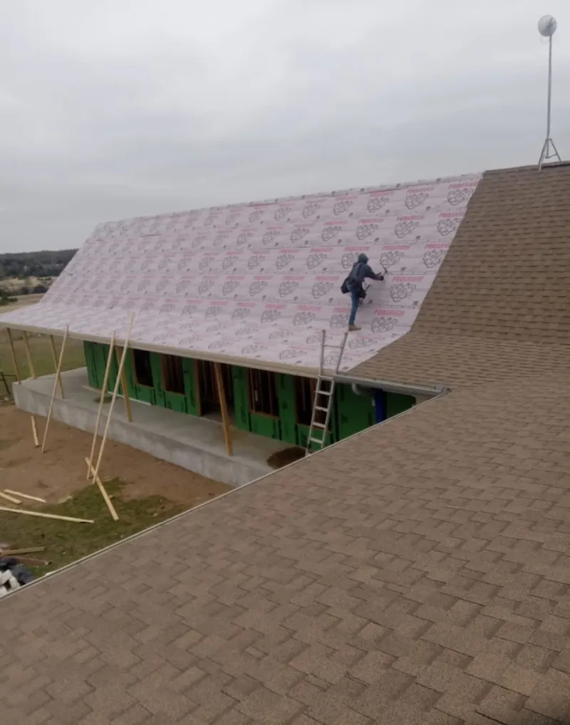 Worker preparing underlayment for a metal roof installation in Huntsville